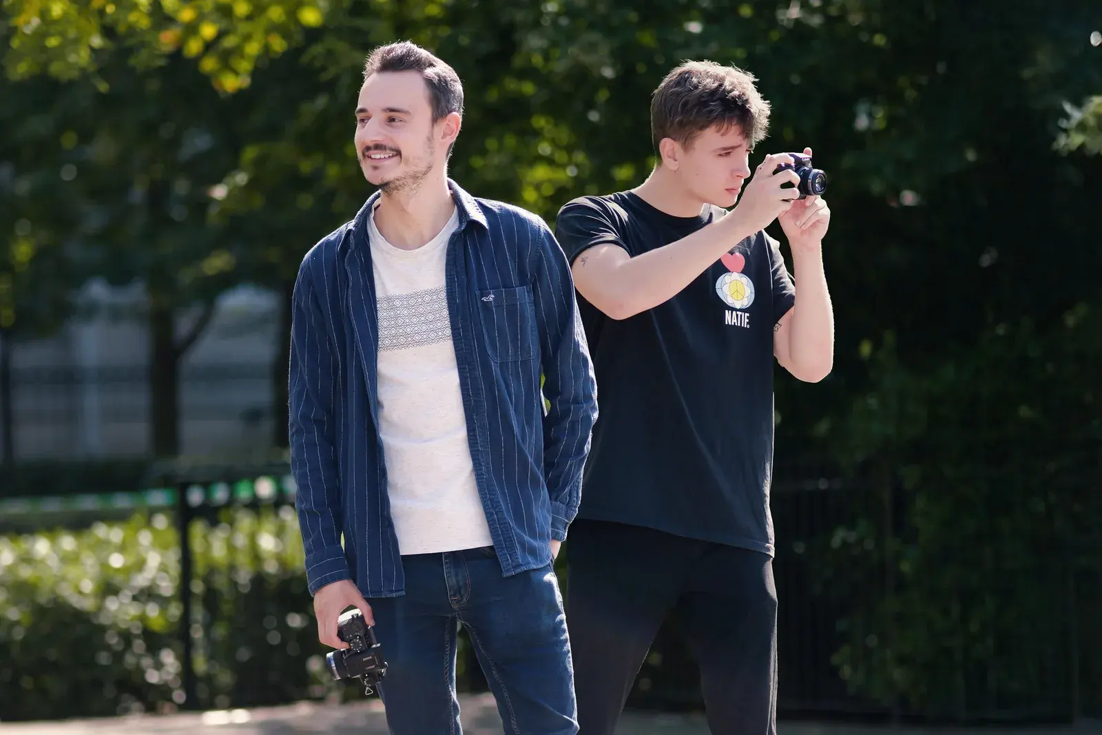 Deux membres de l'équipe d'Aeon Studio en extérieur, appareils photo en main, l'un d'eux en train de cadrer